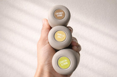 A hand holding three Roon mini deodorant tubes