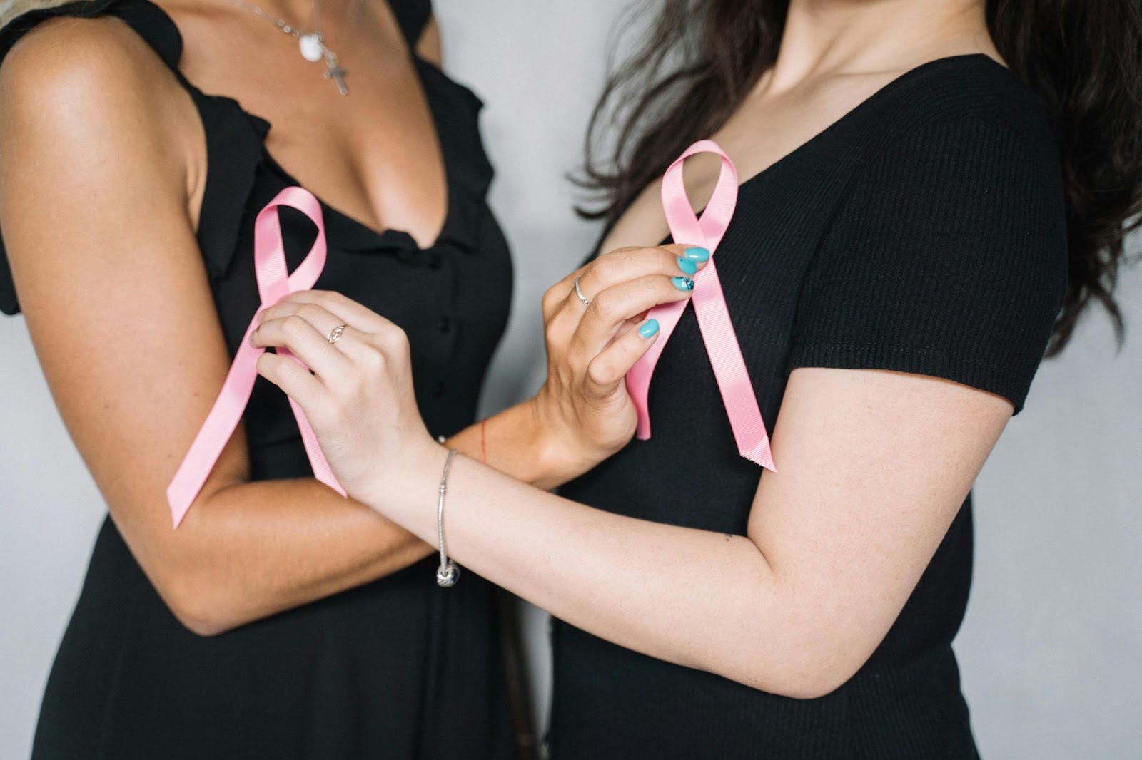 Two women holding a breast cancer awareness ribbon.