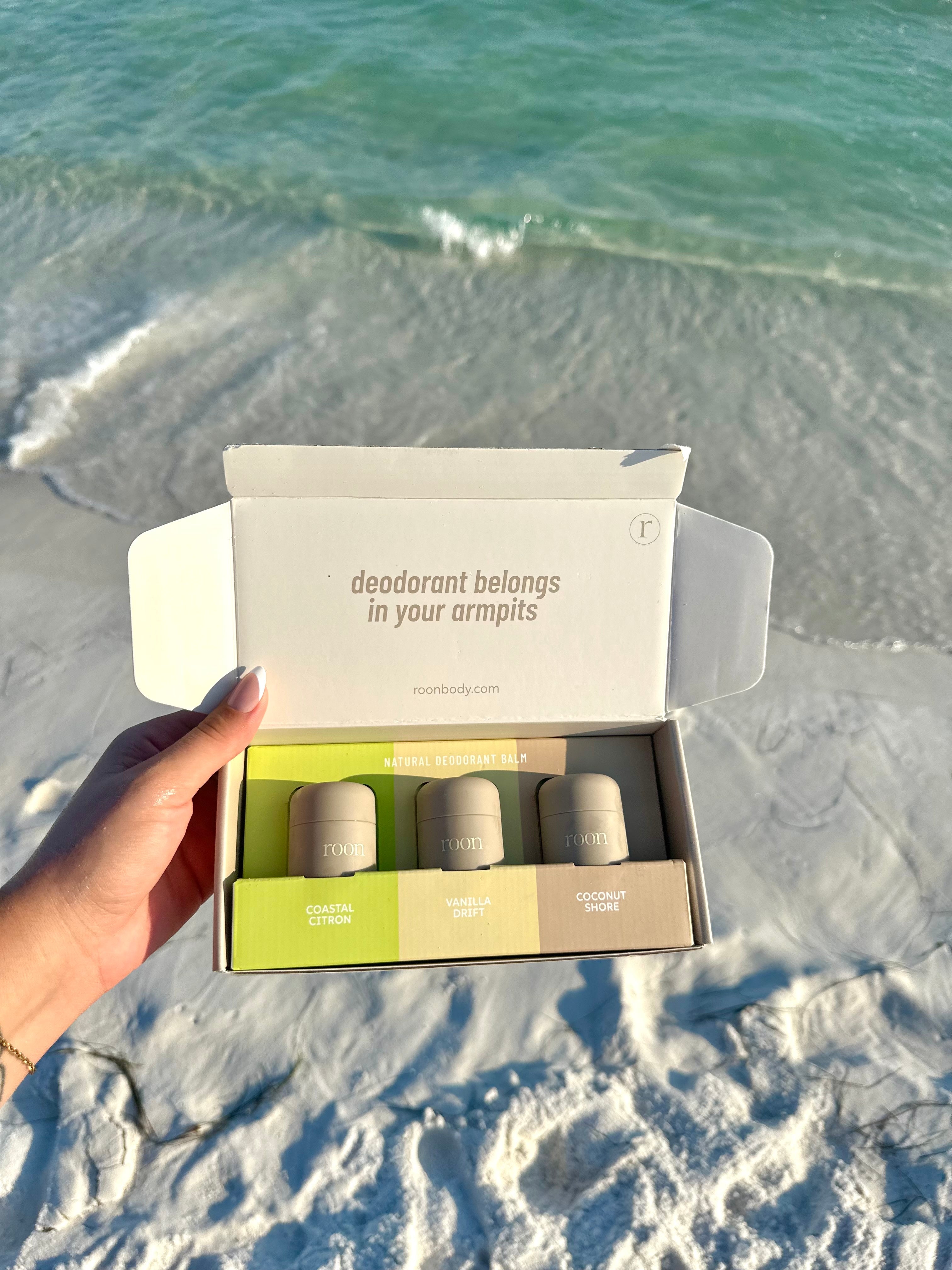 The Roon Discovery Set mailer box opened at the shoreline — three mini deodorant balms: Coastal Citron, Vanilla Drift and Coconut Shore