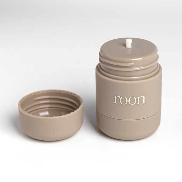 An open Roon tube with the cap beside it and a bead of balm twisted up through the applicator